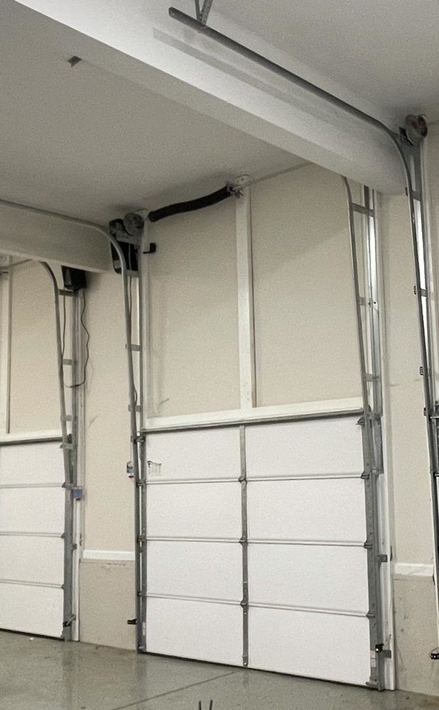 White commercial garage door opening upwards. Interior view, silver metal frame.