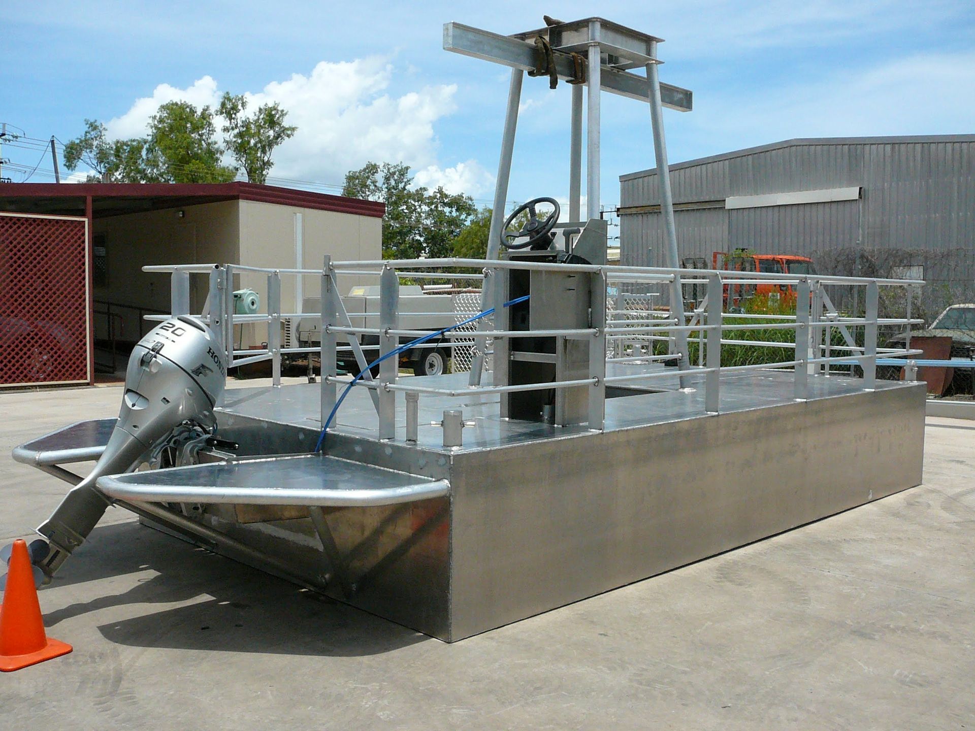 Metal Boat With Motor and Railings on a Concrete Lot, Beside a Red Shed — Greville Fabrication in Girraween, NSW