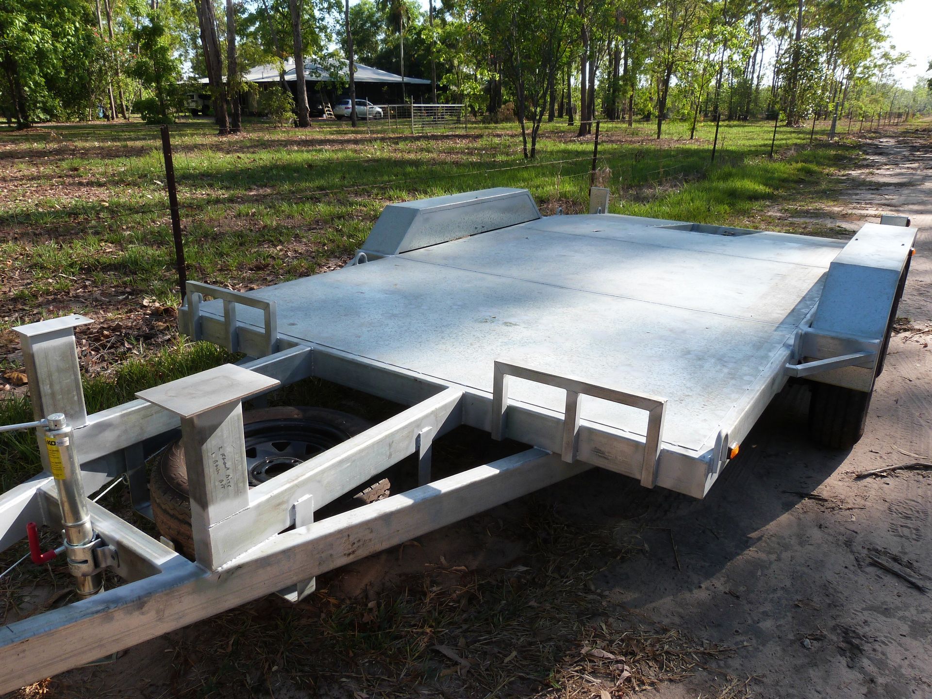 Silver Flatbed Trailer on Dirt, Ready for Transport Outdoors — Greville Fabrication in Girraween, NSW