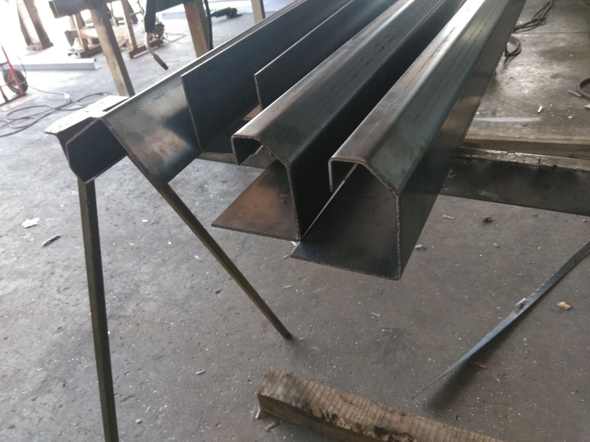 Stacked Black Metal Beams on a Workshop Floor, With Welding Scraps Nearby — Greville Fabrication in Girraween, NSW