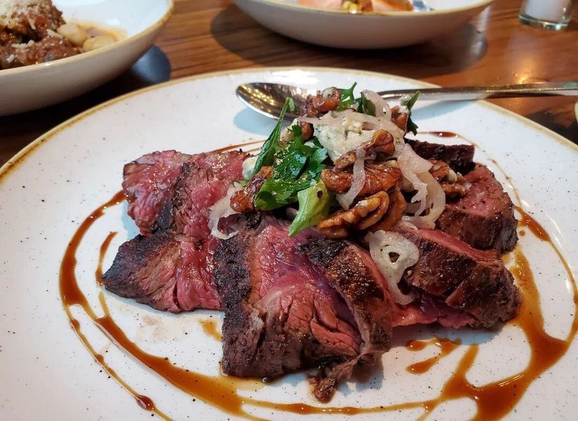 A white plate topped with meat and vegetables on a table.