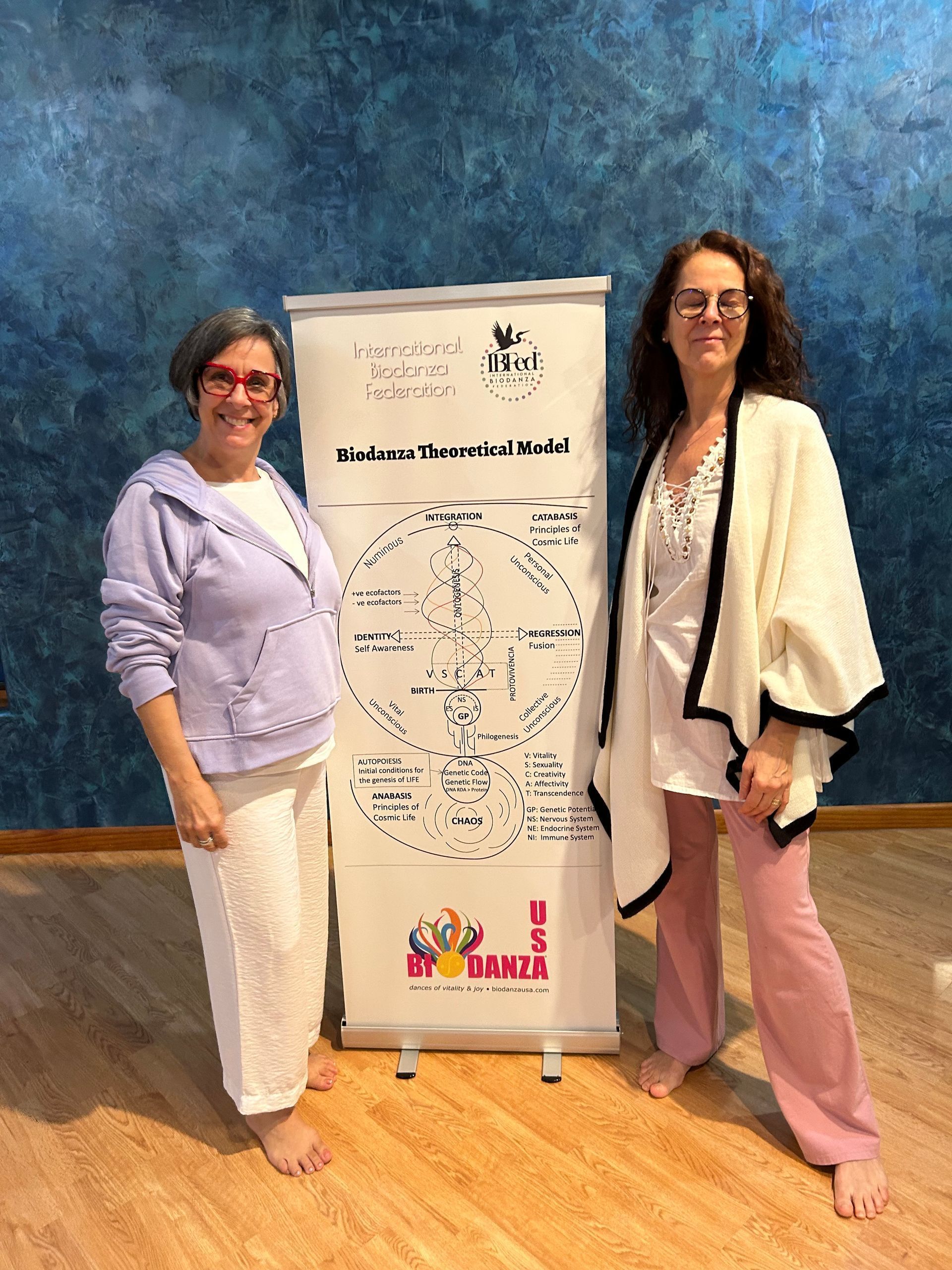 Two women are standing next to each other in front of a whiteboard.