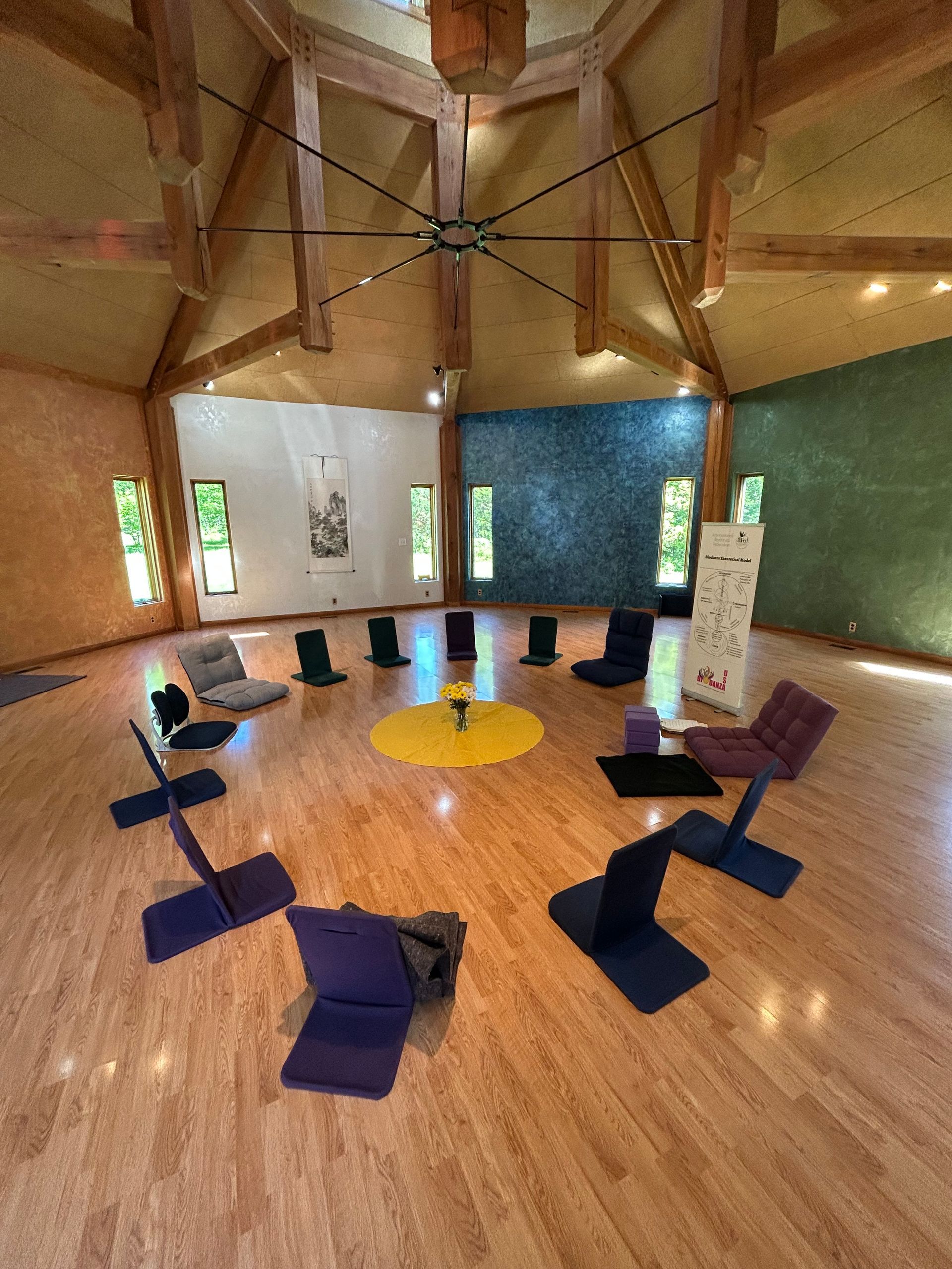 A group of chairs are sitting in a circle on a wooden floor in a room.