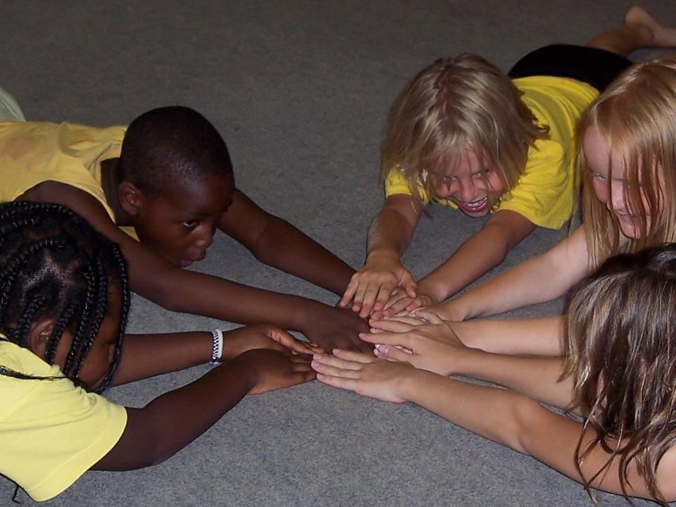 A group of children laying on the floor with their hands together
