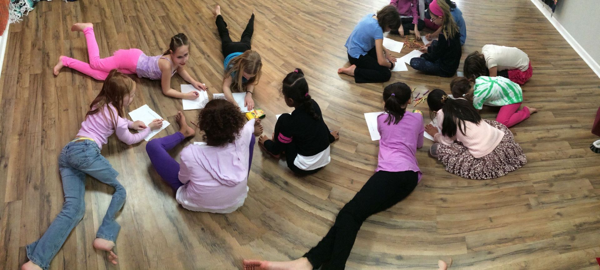 A group of children are laying on the floor in a circle.