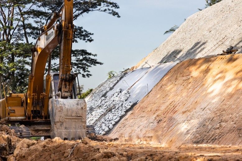 A Yellow Excavator is Moving Dirt on a Construction Site — Payton Civil Products in Kingaroy, QLD