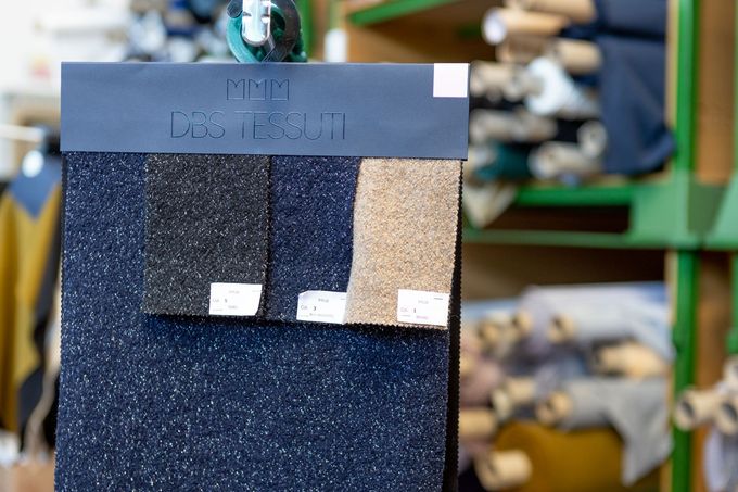Campioni di tessuto nei toni del blu scuro, del blu navy e del beige esposti in uno showroom tessile.