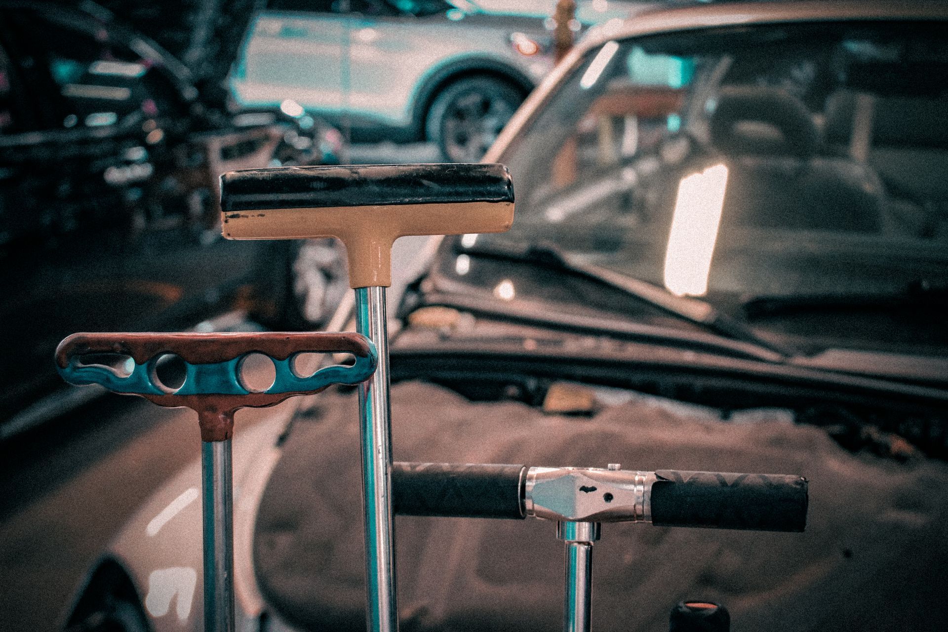 Close-up of bicycles in a garage, with handlebars and car seats in the background.