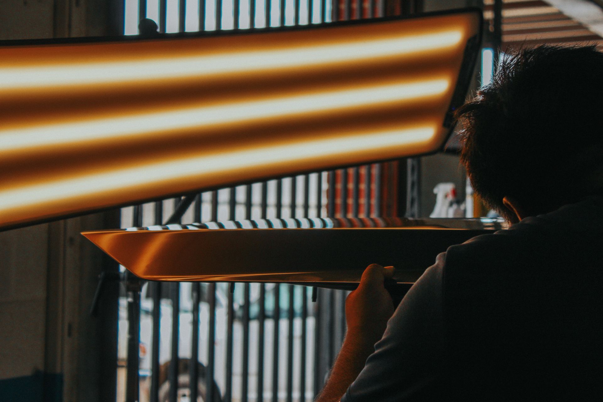 Person holding a glowing orange, striped light panel in a dim room