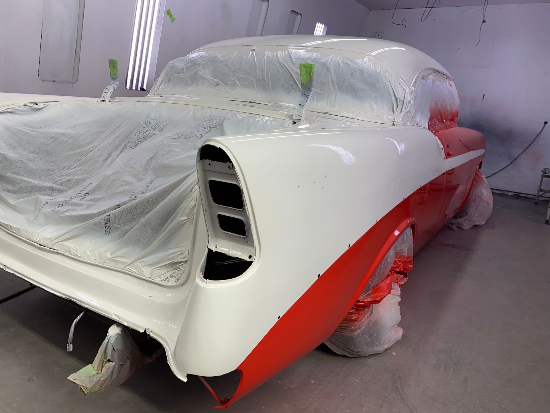 Classic car partially painted red and white in a workshop.