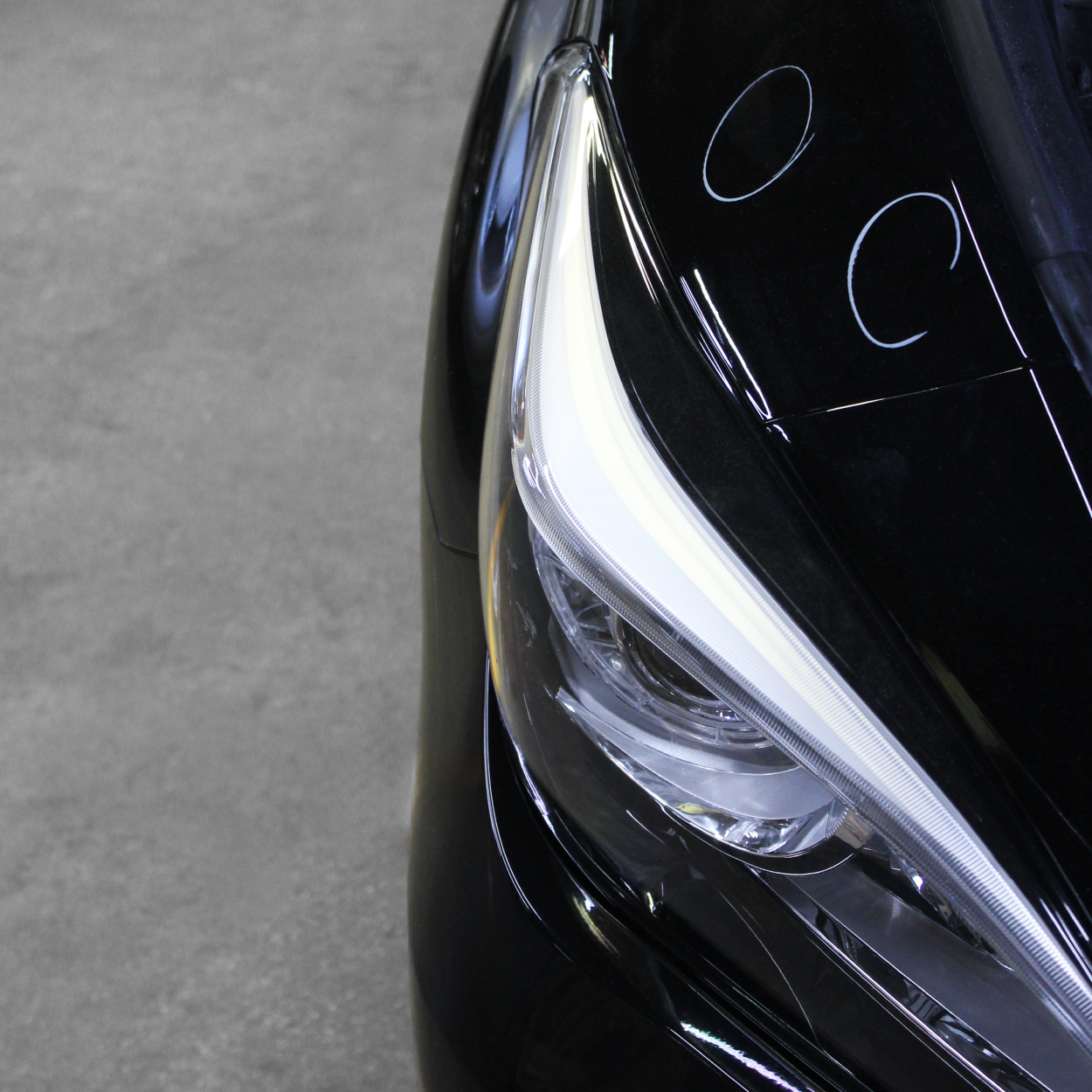 Close-up of a sleek black car headlight with bright white LED accents