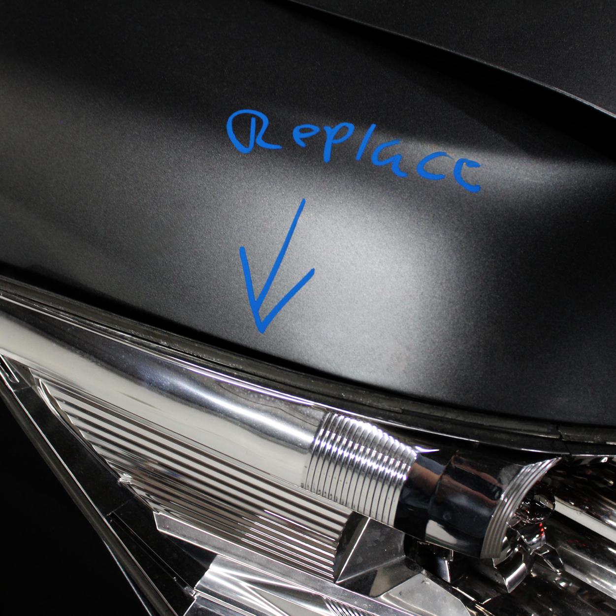 Close-up of a car headlight assembly with a blue “Replace” note and arrow pointing to the lens seam.
