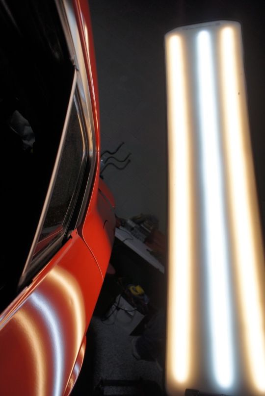 Close-up of a sleek black car headlight with bright white LED accents
