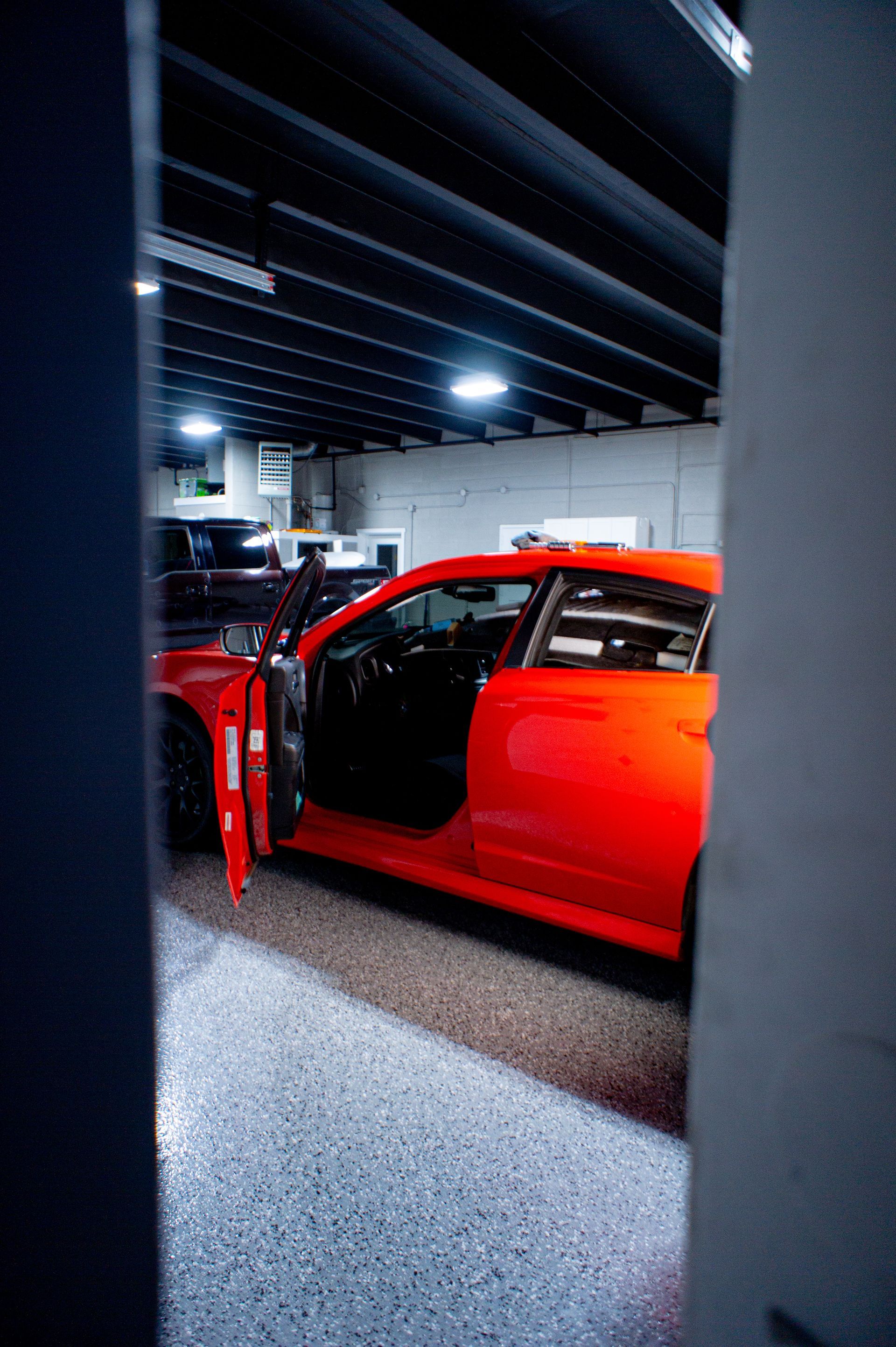 Person holding a device near a car roof under bright lights in a garage