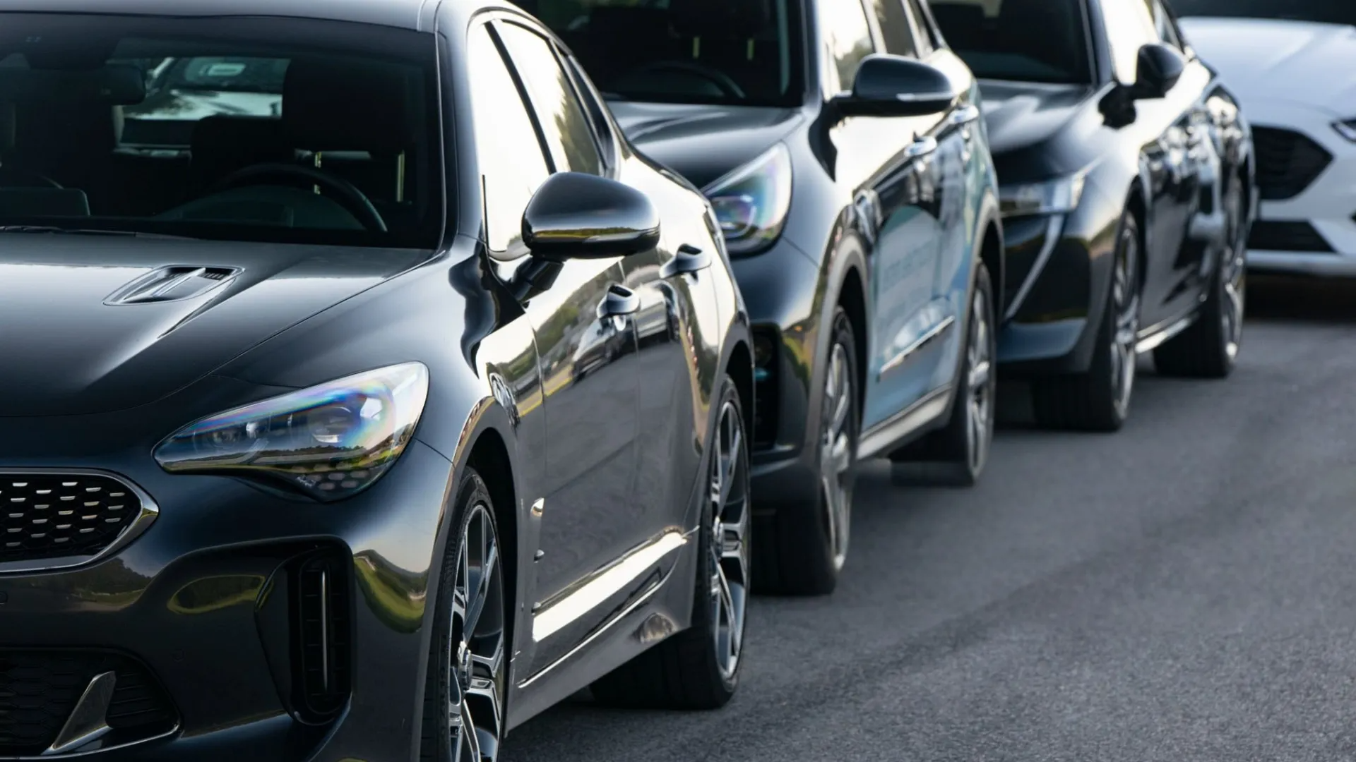 Line of black cars parked on asphalt.