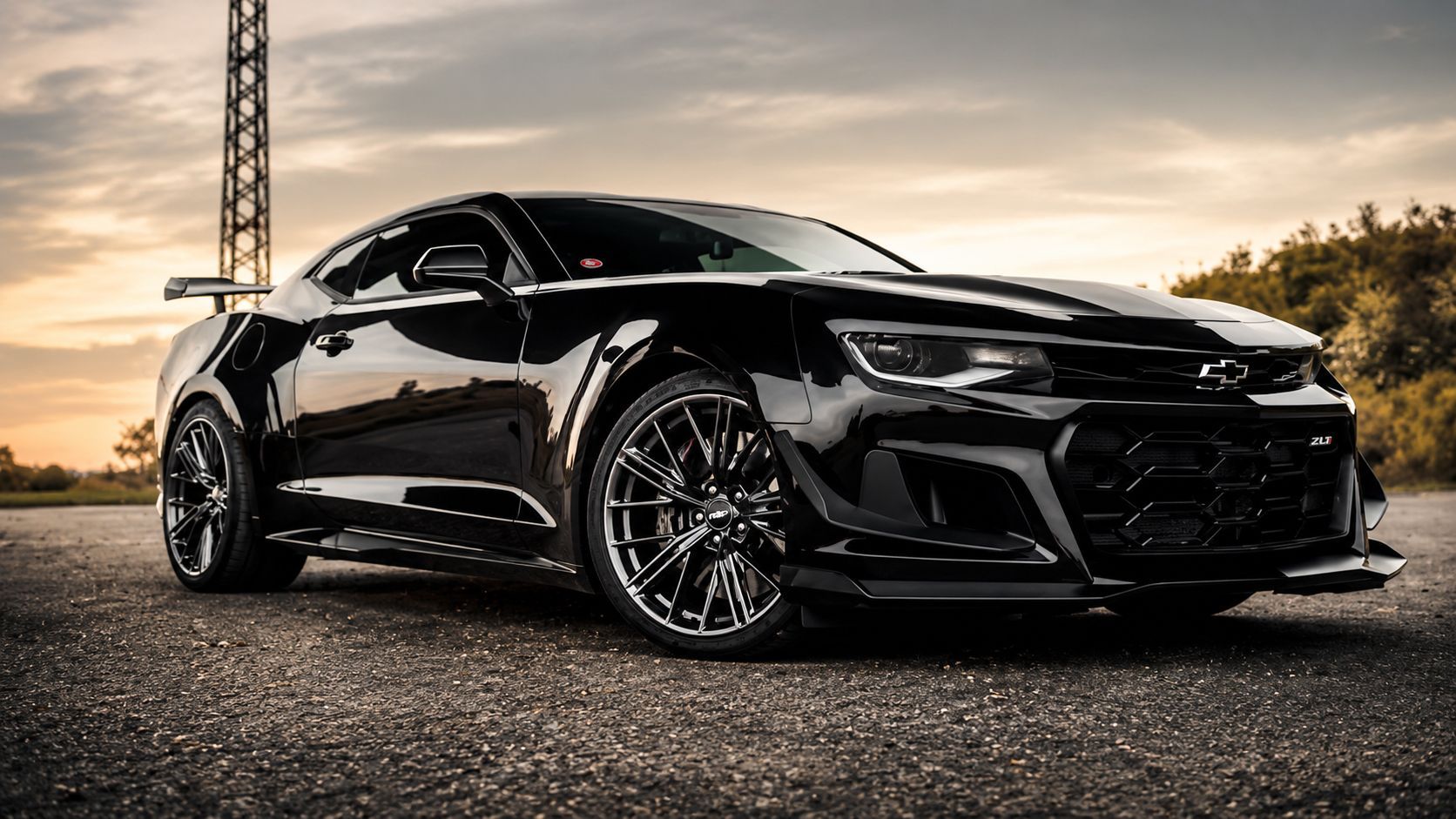 Black sports coupe parked on pavement at sunset, with a tower in the background.