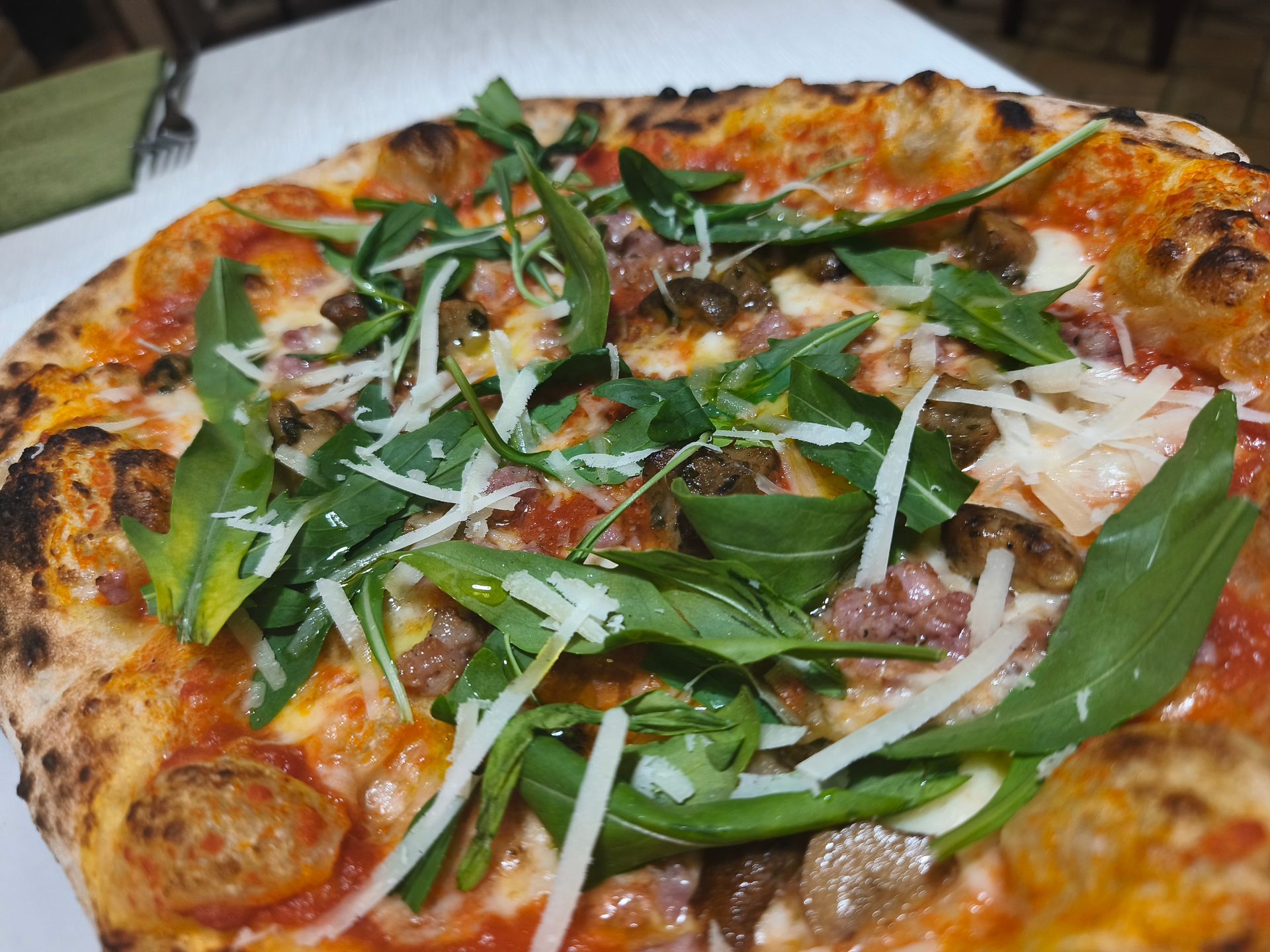 Pizza condita con rucola, formaggio grattugiato e salsa di pomodoro su un piatto