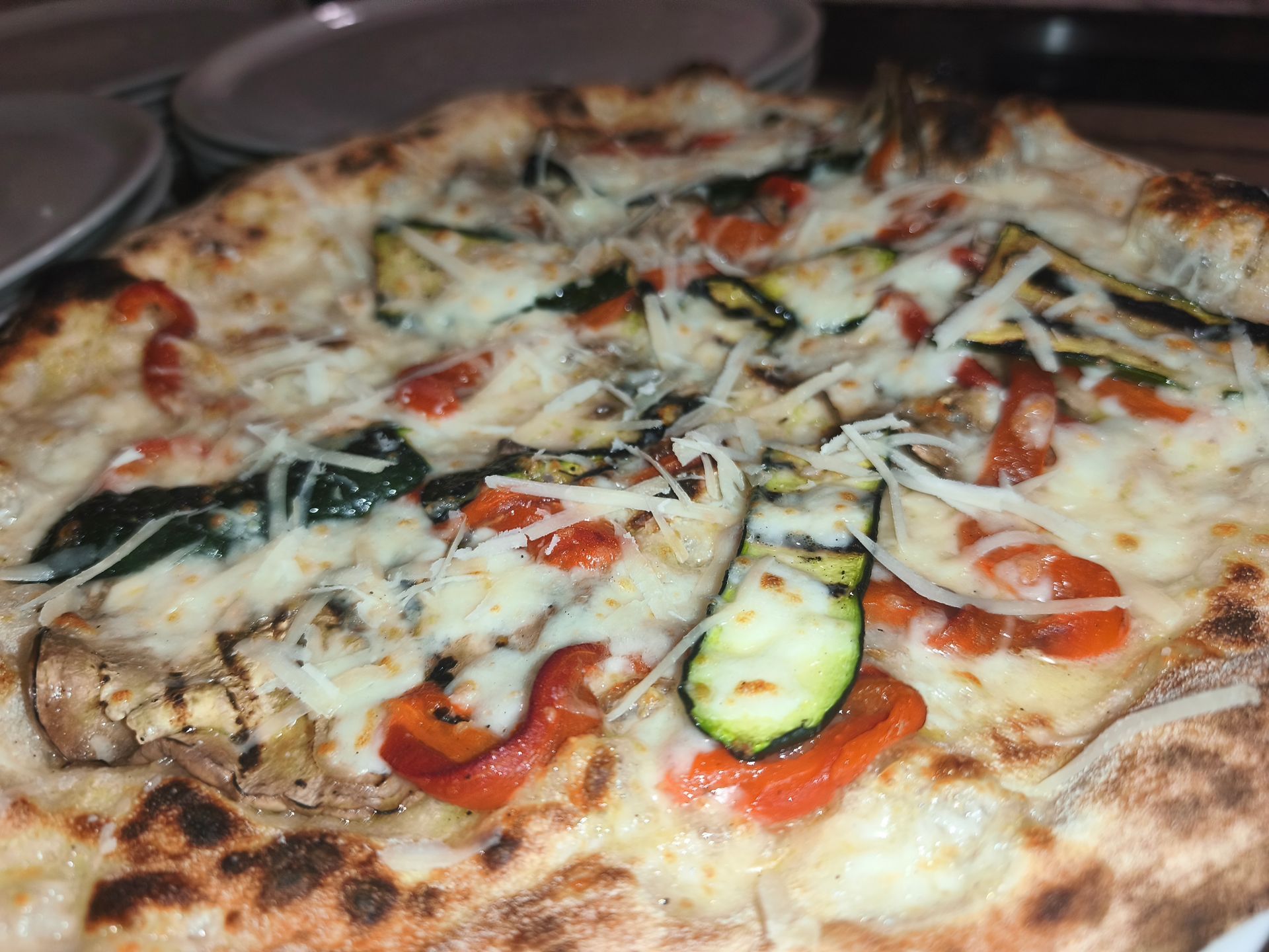 Pizza vegetariana al formaggio con zucchine, pomodoro ed erbe aromatiche, servita su un piatto.