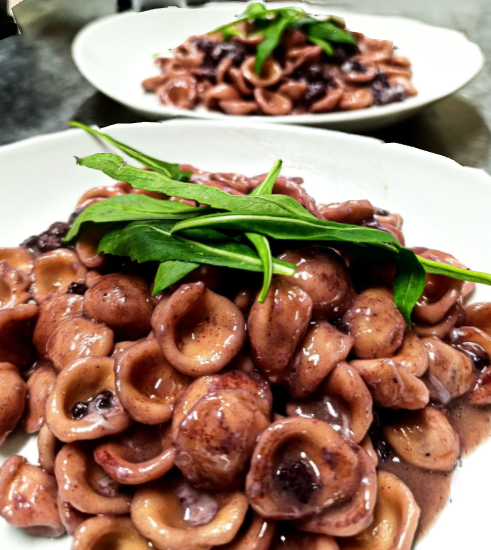 Primo piano di funghi saltati in padella e guarniti con erbe aromatiche su piatti bianchi.