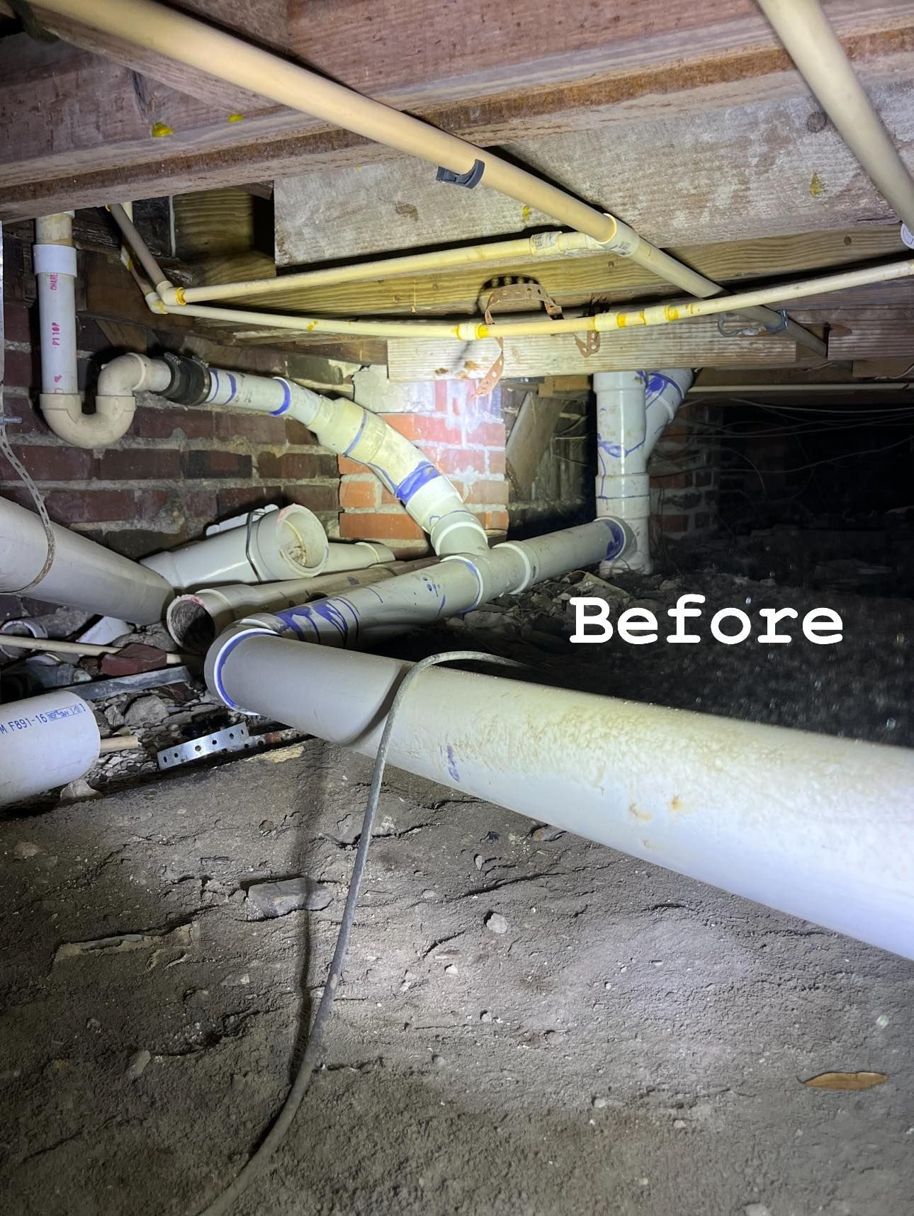 Crawl space with exposed white pipes and brick wall, lit by flashlight, labeled “Before”