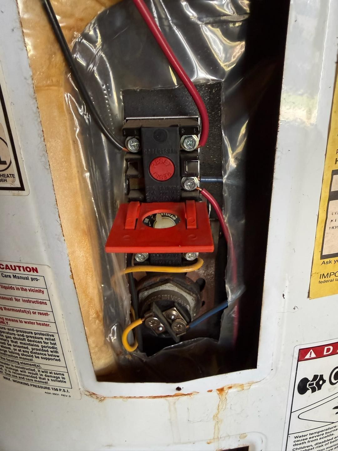 Red gas valve and wiring inside a metal furnace or appliance compartment.