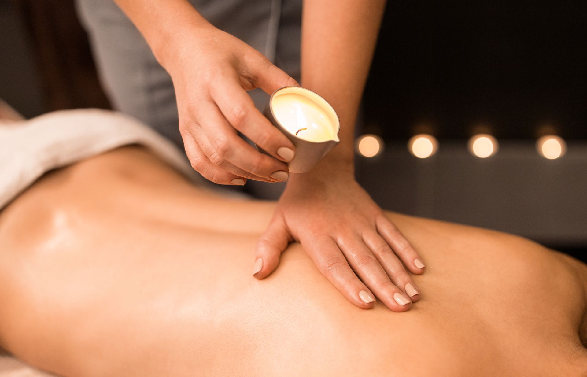 A hand holds pink Himalayan salt near spa elements: a stack of stones, plumeria flowers, and a herbal compress on wood. A hand holds pink Himalayan salt near spa elements: a stack of stones, plumeria flowers, and a herbal compress on wood.