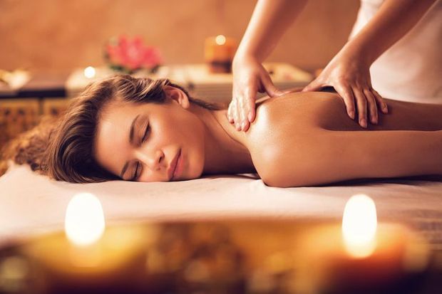 A person receives a relaxing back massage in a spa, with soft, blurred candlelight in the foreground. A person receives a relaxing back massage in a spa, with soft, blurred candlelight in the foreground.