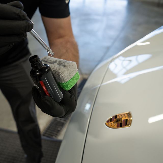 A person is polishing the hood of a blue car.