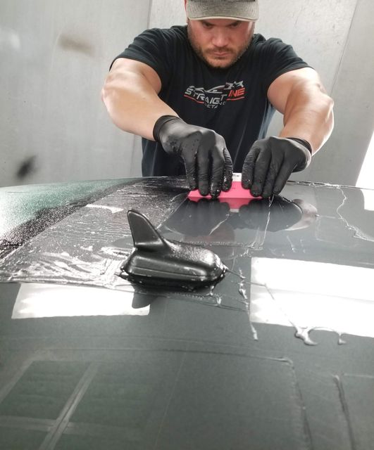 A person is cleaning a car with a blue sponge.