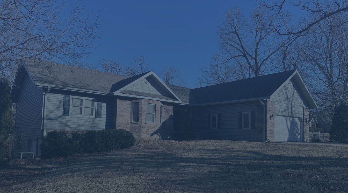 Suburban house with a gabled roof and attached garage in a snowy yard under a blue sky