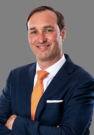 A man in a suit and tie is smiling with his arms crossed.
