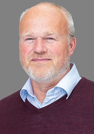 A man in a white shirt and red tie is smiling for the camera.