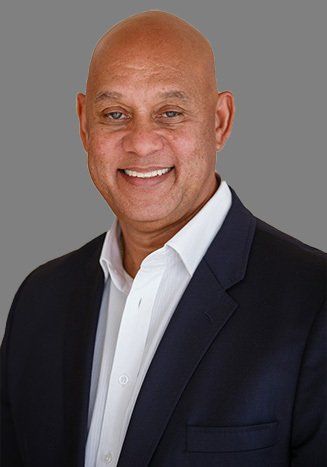 A bald man in a suit and white shirt is smiling for the camera.