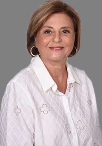 A woman wearing a white shirt and earrings is smiling for the camera.