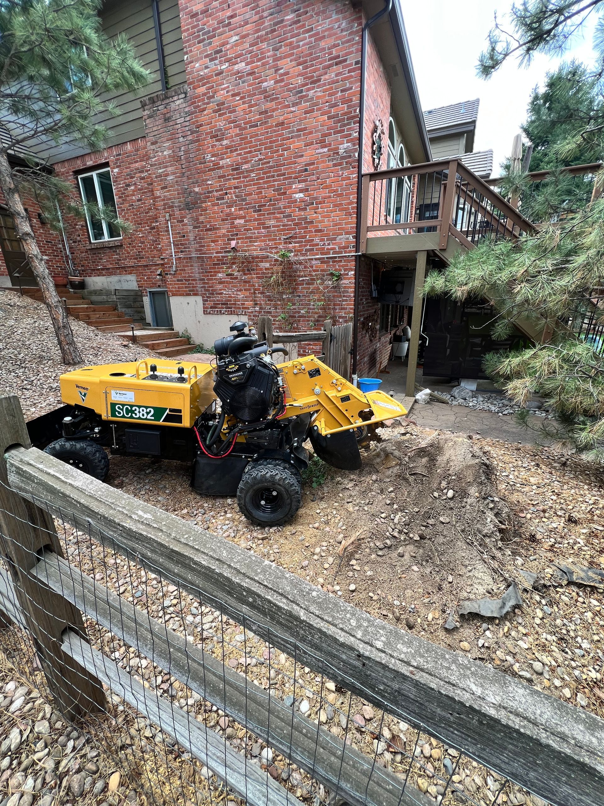 A person is using an excavator to remove a tree stump from the ground.