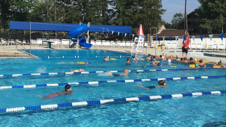 Swimming pool with children taking a swimming lesson, blue and white lane markers, instructor.