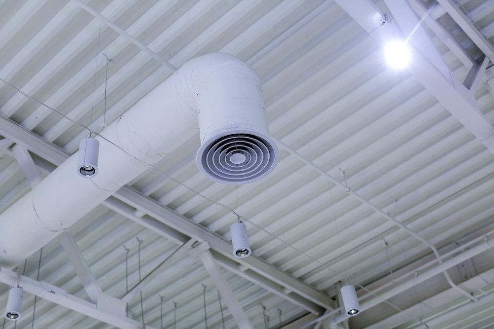 A White Air Duct is Hanging From the Ceiling of a Building — Northside Air Conditioning Services In Aspley, QLD
