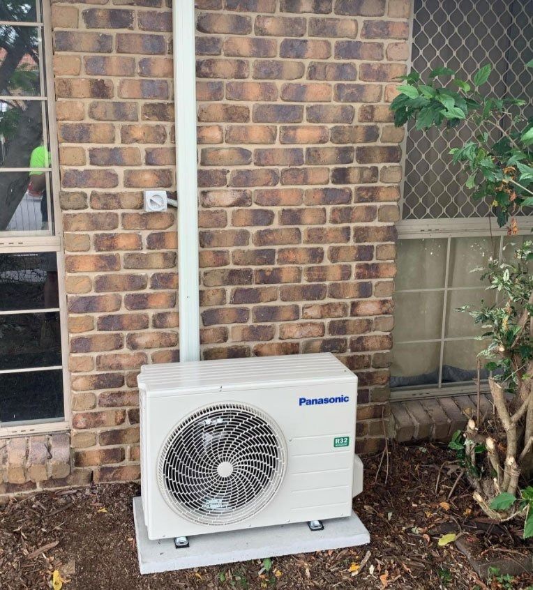 A Panasonic Air Conditioner is Mounted on the Side of a Brick Building — Northside Air Conditioning Services In Aspley, QLD