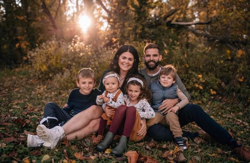 Picture of Eli Shipley with his wife Bethany Shipley and their four children taken in a wooded area wit the sun setting behind them.