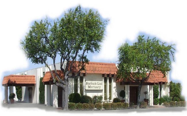 Building with red tile roof, greenery, and sign 
