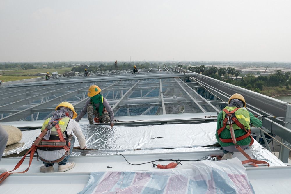 A group of construction workers are working on the roof of a building — Experienced Roofer in Rangeville, QLD