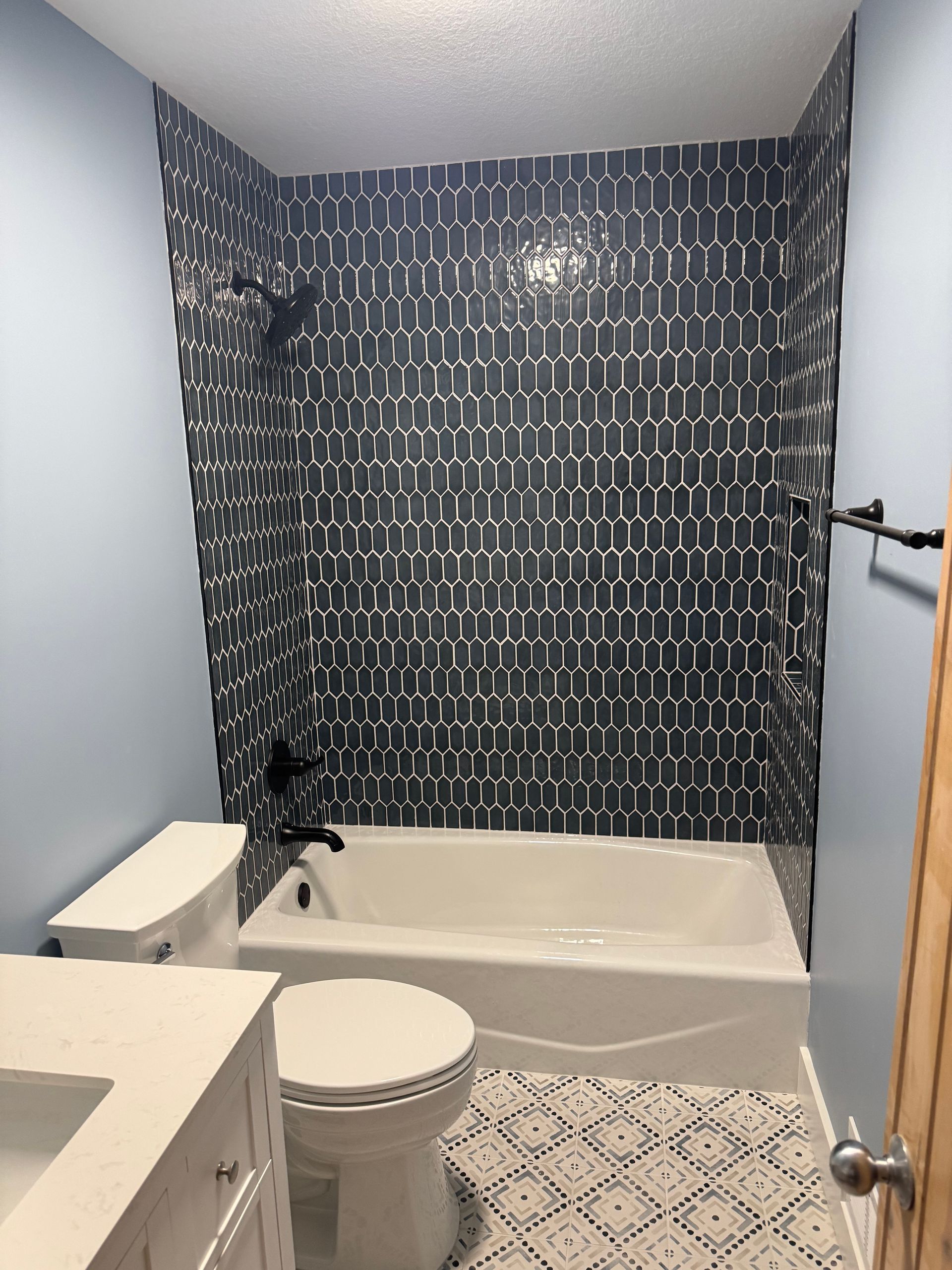Small bathroom with a bathtub, toilet, and patterned blue-and-white shower curtain.