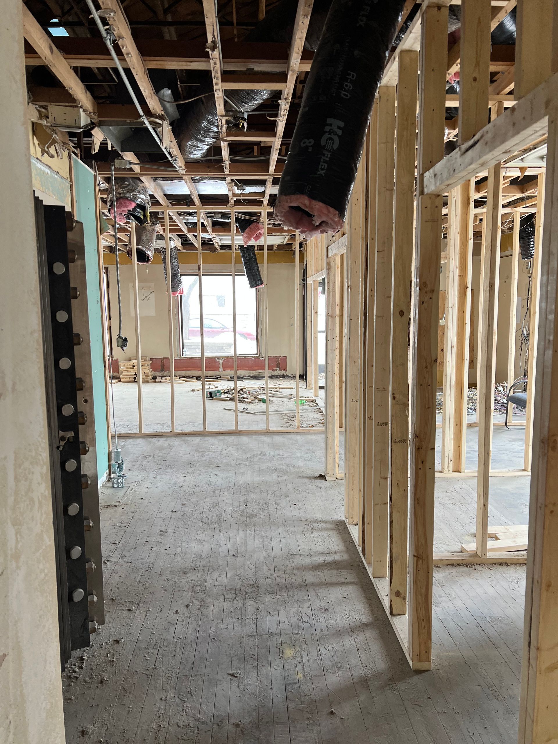 Unfinished home interior with exposed wooden framing, open doorway, and concrete floor during construction