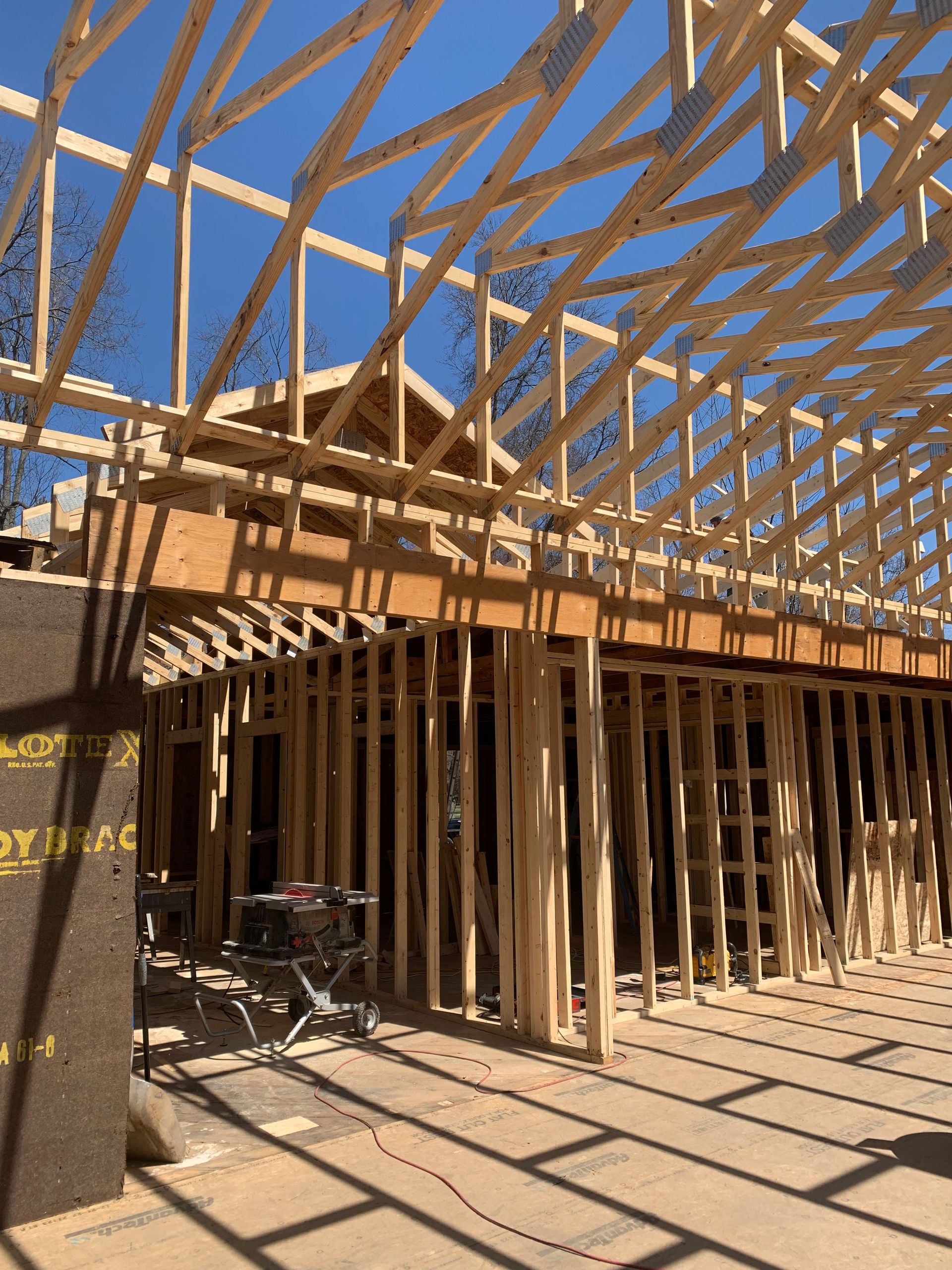 Wood-framed house under construction with exposed roof trusses and a bicycle in the foreground