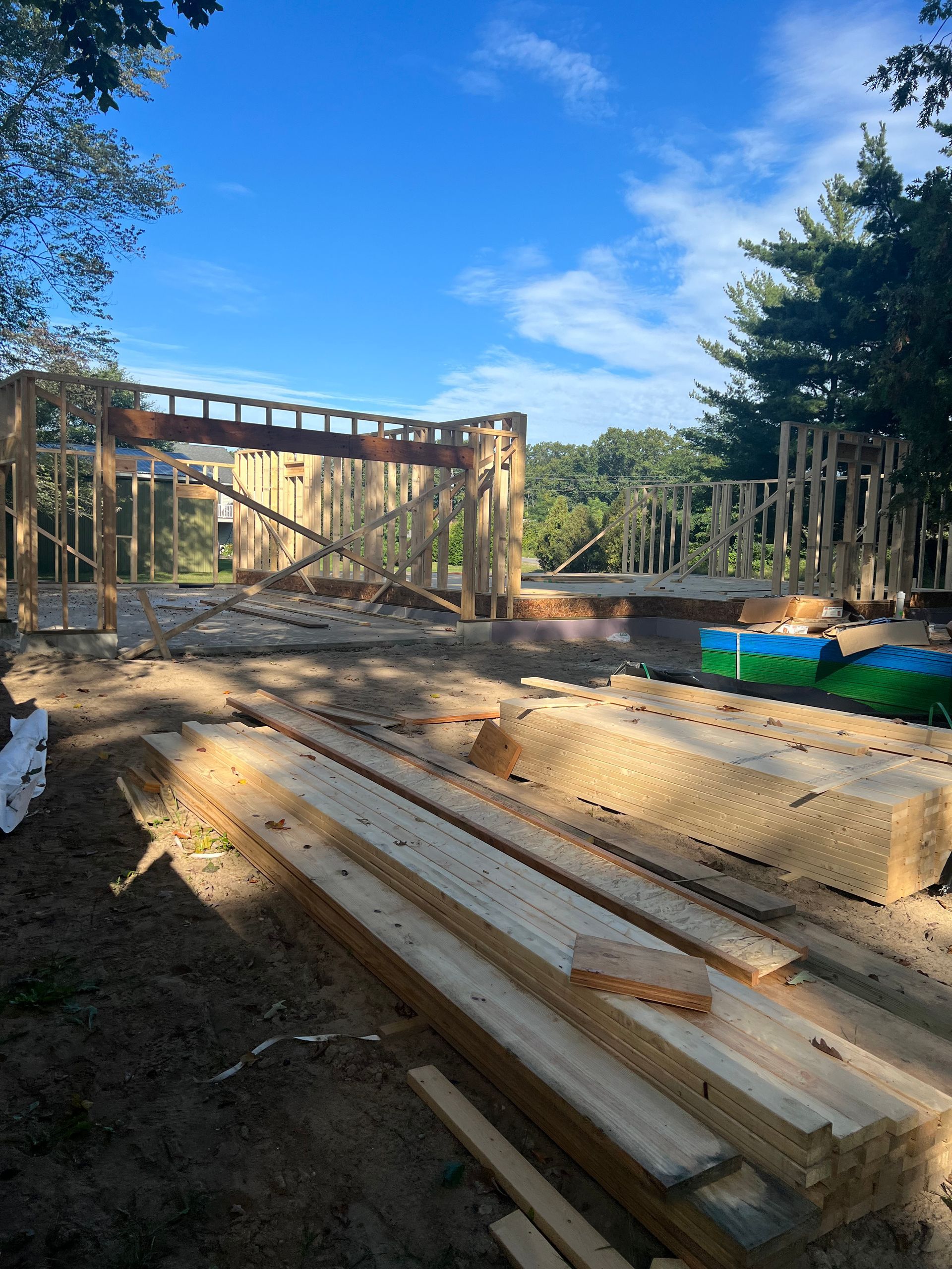 Wood framing and lumber at a house construction site under a blue sky