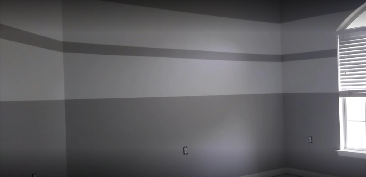 A room with gray and white striped walls. A window with blinds is visible.