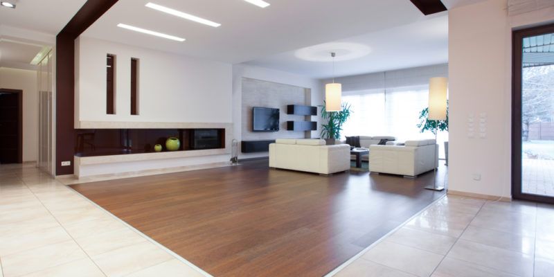 Modern living room with fireplace, white furniture, wood floor, and large windows.