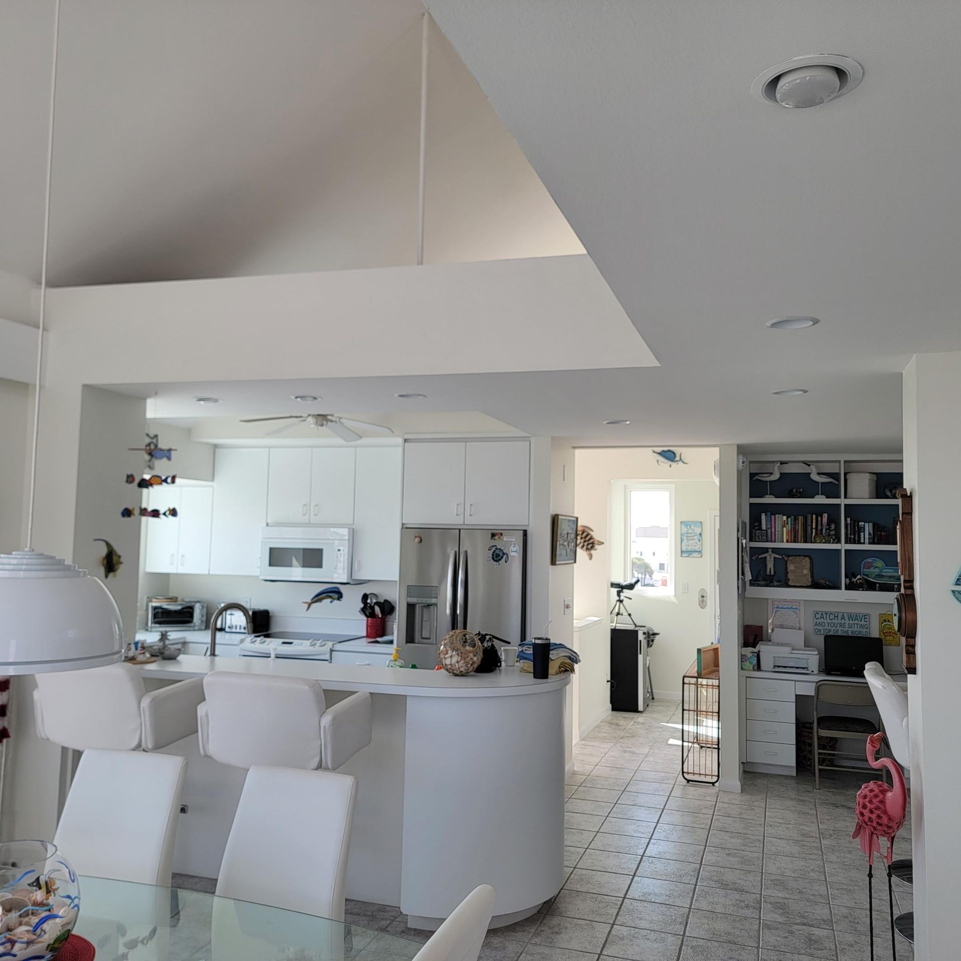 Bright white kitchen with island, chairs, and built-in desk.