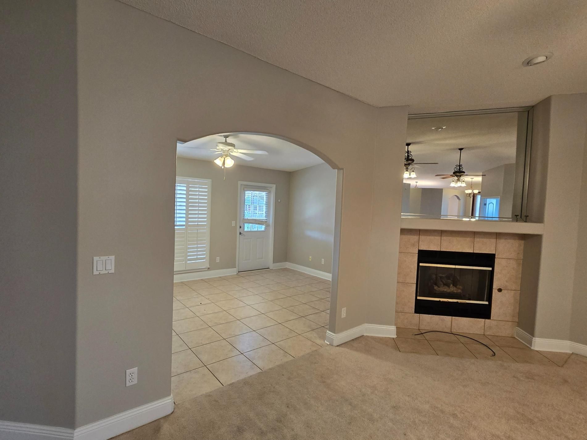 Living room with a fireplace, arched doorway, and mirrored wall.