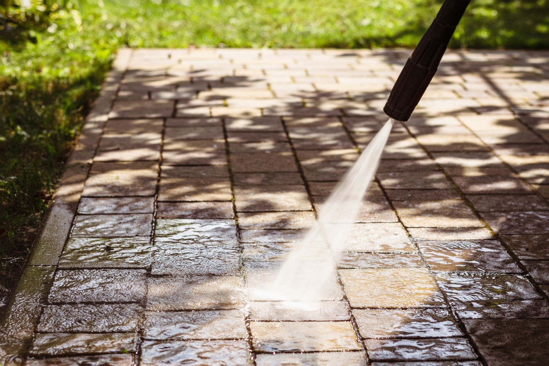 Pressure washer cleaning a brick patio, removing dirt.